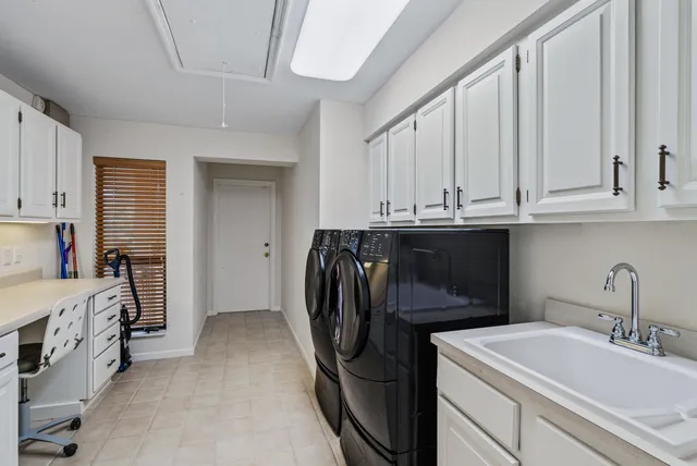 a utility room with stainless steel appliances a sink and a refrigerator