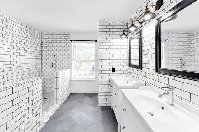 a bathroom with a double vanity sink mirror and a bathtub