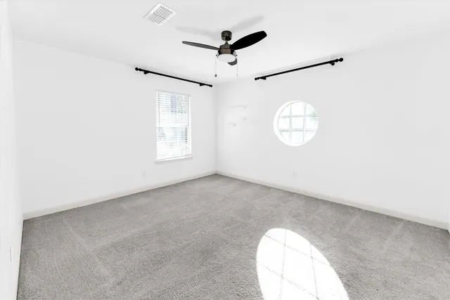 an empty room with windows and ceiling fan