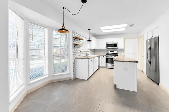 a kitchen with stainless steel appliances granite countertop a stove top oven a refrigerator a sink and dishwasher