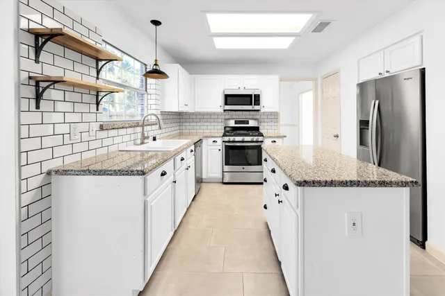 a kitchen with stainless steel appliances granite countertop a sink and a refrigerator