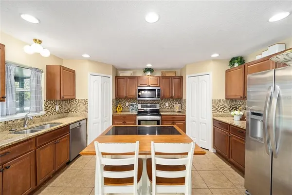 a kitchen with granite countertop kitchen island stainless steel appliances a refrigerator a stove a sink a dining table and chairs