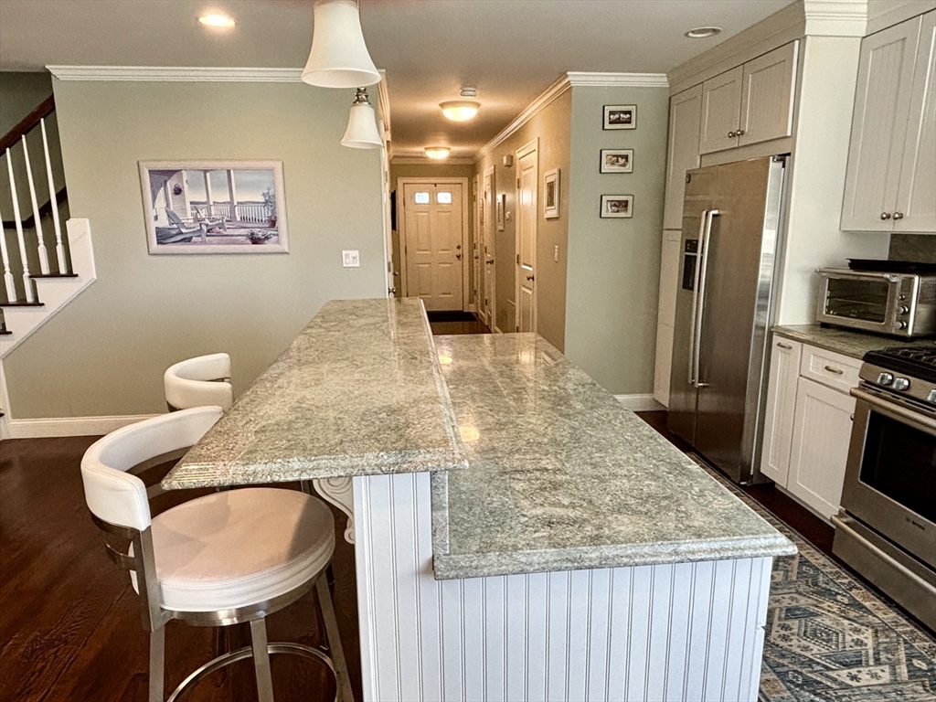 9 Endicott Street, Unit B Danvers, MA 01923 - Photo 5 of 42 a kitchen with stainless steel appliances granite countertop a kitchen island a stove a refrigerator a oven with a dining table and chairs