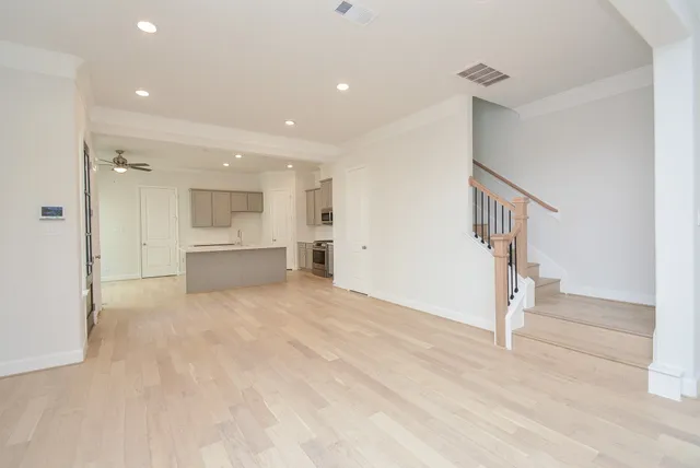 a view of empty room with wooden floor and kitchen