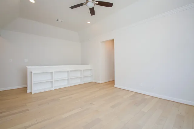 an empty room with ceiling fan and window
