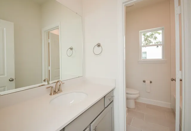 a bathroom with a granite countertop sink a toilet and a mirror