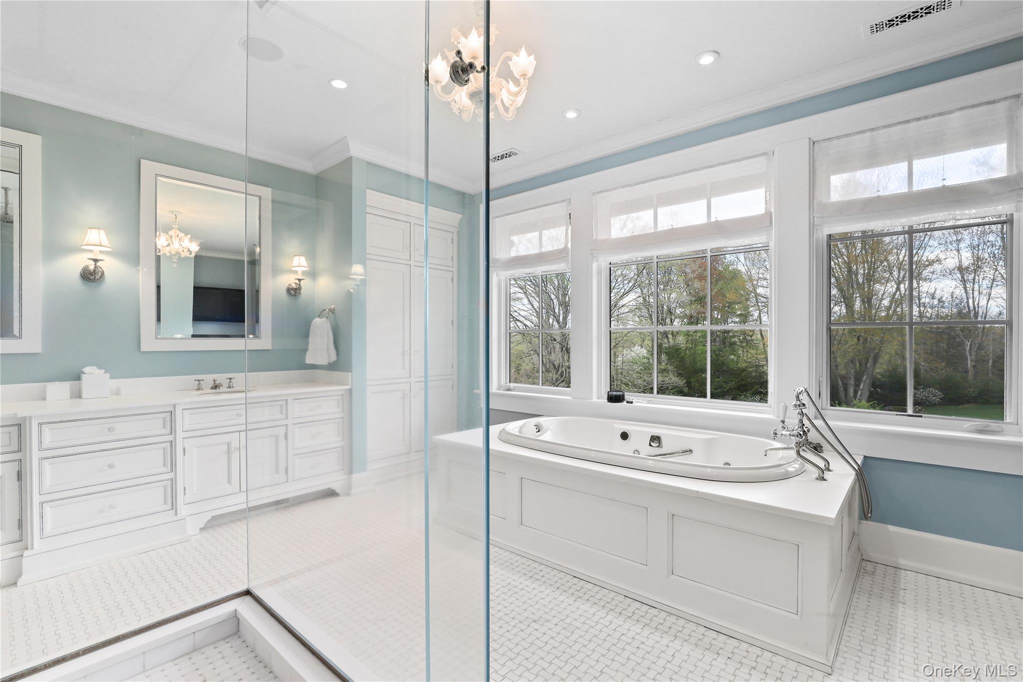 10 Upland Road North Bedford, NY 10506 - Photo 19 of 36 a bathroom with a sink a large mirror and a bathtub next to a window
