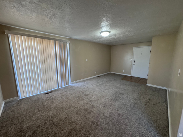2182 West 5600th Street South Roy, UT 84067 - Photo 4 of 11 Spacious interior featuring neutral carpeting, light-toned walls, and a large sliding glass door with vertical blinds