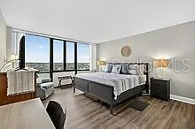 a bedroom with a bed and large windows