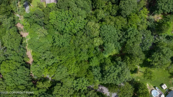 an aerial view of residential house with outdoor space and trees all around