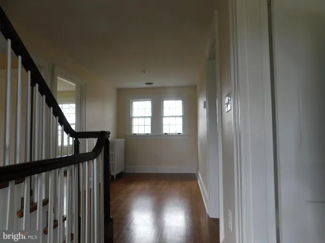 a view of a hallway with wooden floor and stairs