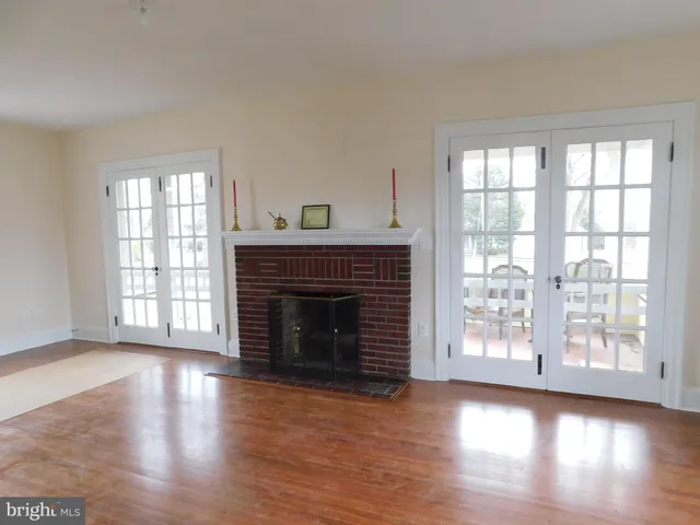 an empty room with wooden floor fireplace and windows