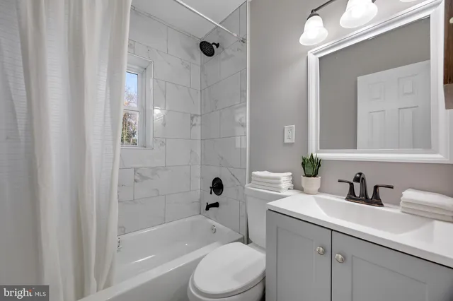 a bathroom with a sink a toilet a mirror a bathtub and shower