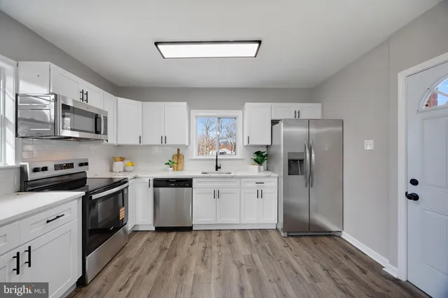 a kitchen with stainless steel appliances granite countertop a refrigerator a stove top oven a sink and dishwasher with wooden floor