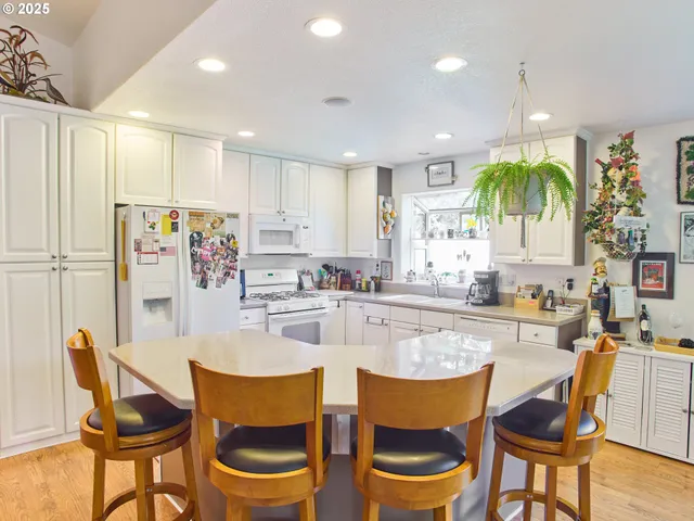 a kitchen with stainless steel appliances granite countertop a dining table chairs and white cabinets