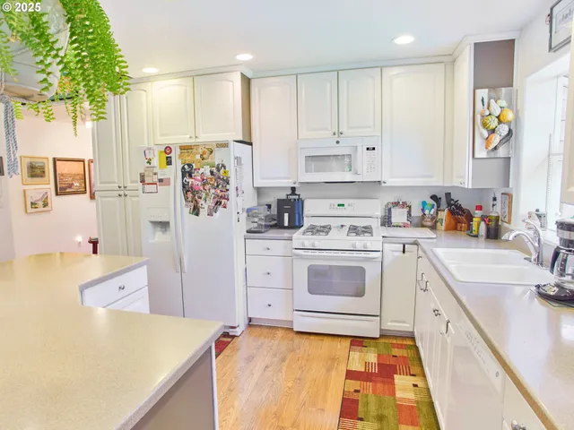 a kitchen with a refrigerator a stove a sink dishwasher and cabinets with wooden floor