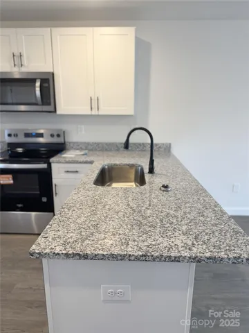 a kitchen with granite countertop a sink and a stove