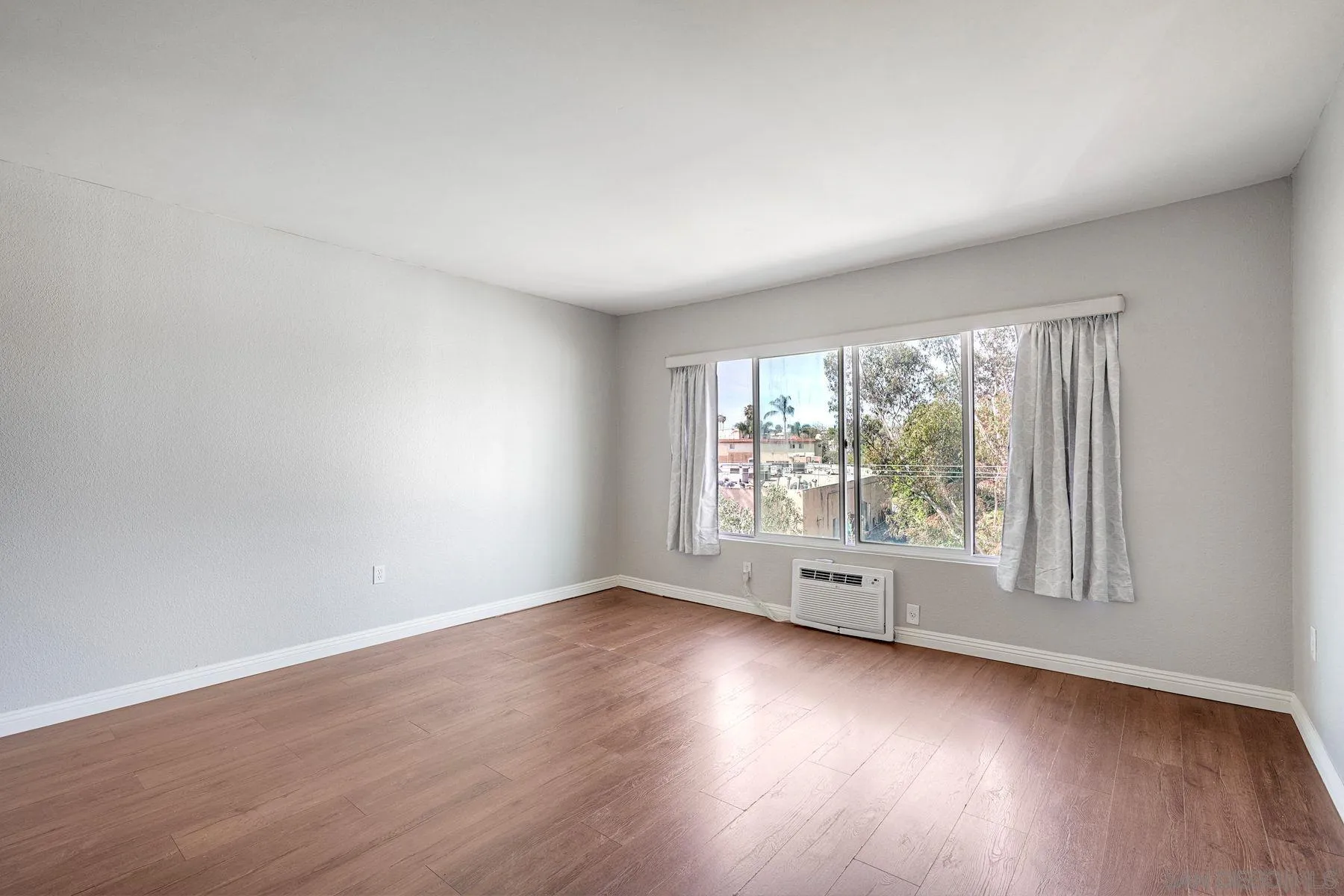 4860 Rolando Court, Unit 75 San Diego, CA 92115 - Photo 9 of 20 an empty room with wooden floor and windows