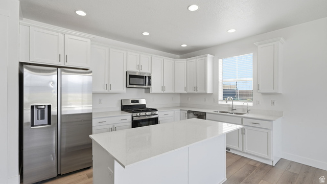 6017 North Sheps Road, Unit C211 Eagle Mountain, UT 84005 - Photo 5 of 25 Well-appointed kitchen featuring white cabinetry, quartz counters, stainless steel appliances, a center island, recessed lighting, and wood-finish flooring