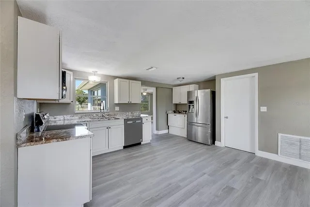 a large kitchen with a wooden floor and stainless steel appliances