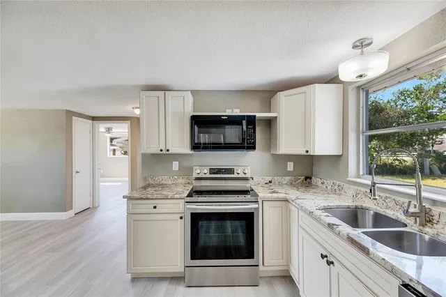 a kitchen with stainless steel appliances granite countertop a sink stove and microwave