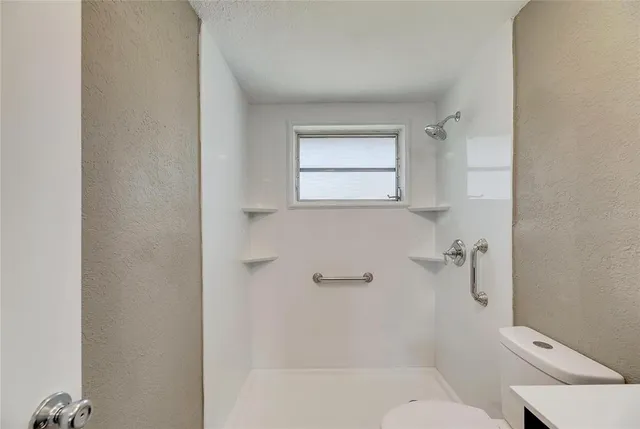 a bathroom with a granite countertop toilet a sink and shower