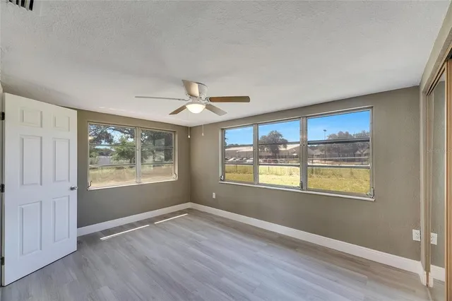 a view of an empty room with a window and wooden floor