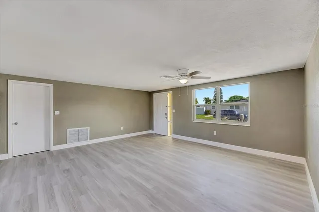an empty room with wooden floor and window