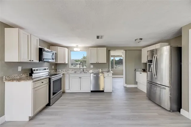 a kitchen with a refrigerator sink and wooden cabinets