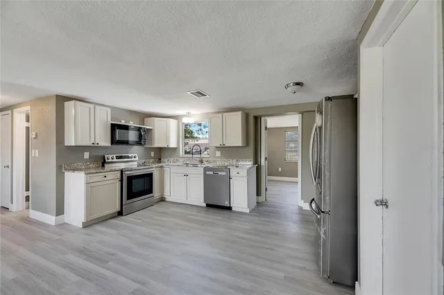 a kitchen with a refrigerator cabinets and wooden floor
