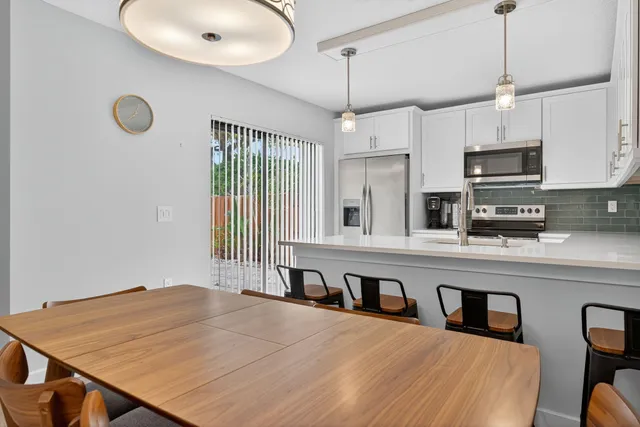 a kitchen with stainless steel appliances granite countertop a stove a sink a refrigerator white cabinets and a granite counter top