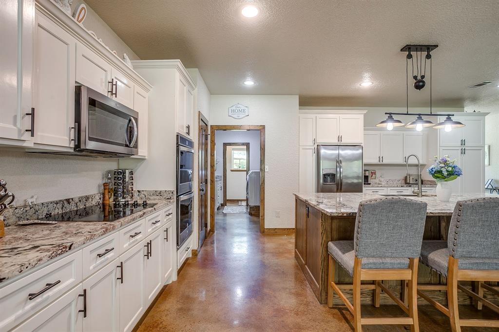 201 Curry Road Waxahachie, TX 75167 - Photo 12 of 40 a kitchen with stainless steel appliances kitchen island granite countertop a stove a sink a refrigerator and a microwave