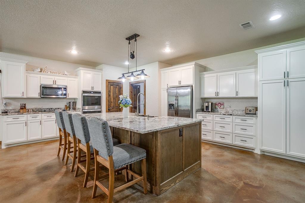 201 Curry Road Waxahachie, TX 75167 - Photo 10 of 40 a kitchen with stainless steel appliances kitchen island granite countertop a table chairs sink and cabinets