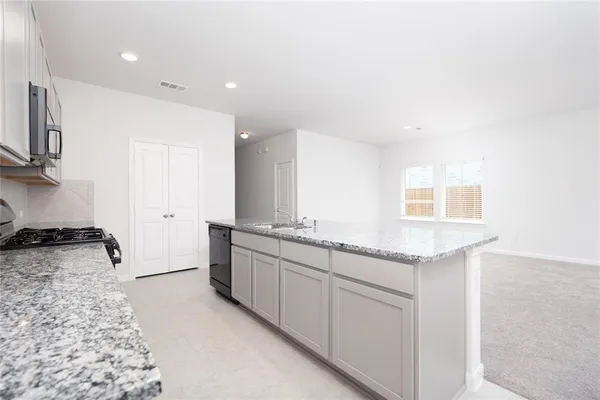 a kitchen with granite countertop a sink and a stove top oven