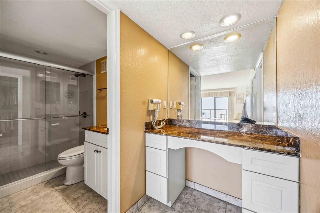 1050 Longboat Club Road, Unit 301 Longboat Key, FL 34228 - Photo 32 of 57 a bathroom with a granite countertop sink a toilet a mirror and shower