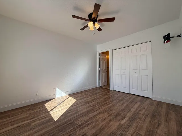 a view of empty room with wooden floor and ceiling fan
