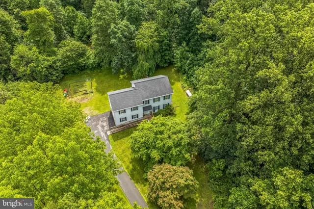 an aerial view of a house with a yard lake and trees all around