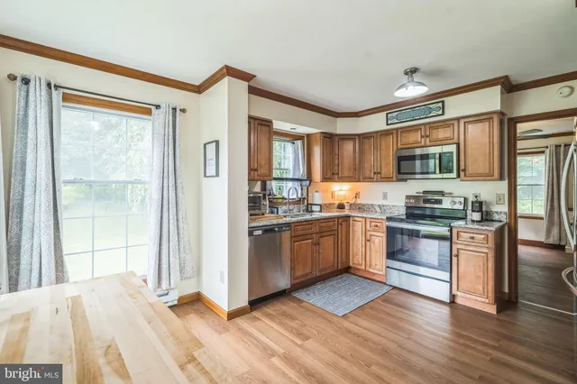 a kitchen with granite countertop stainless steel appliances a stove top oven and a refrigerator