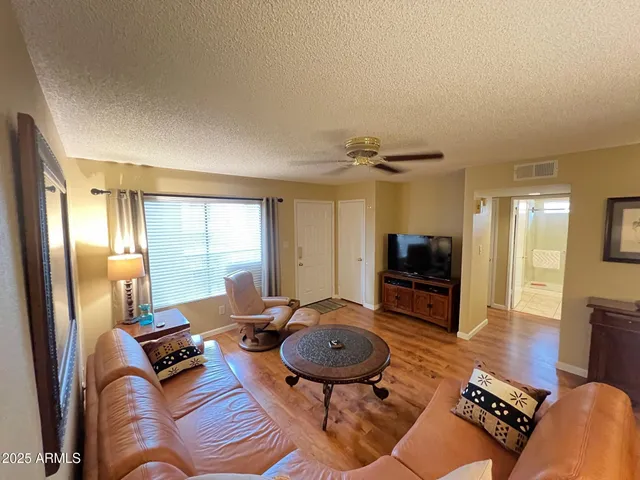 a living room with furniture a flat screen tv and kitchen view