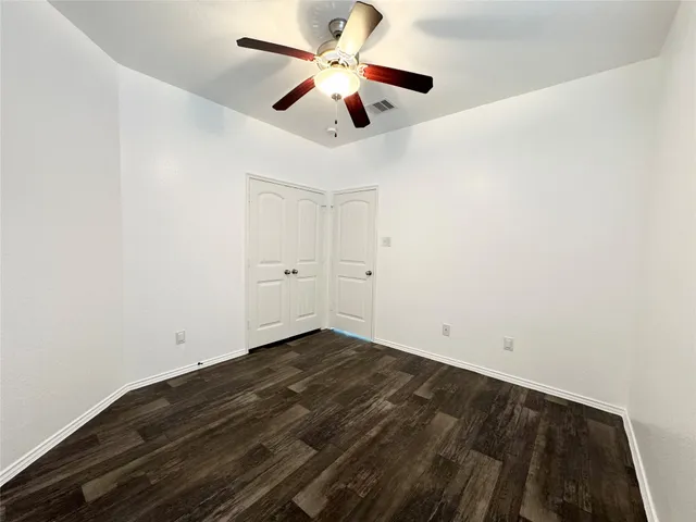 an empty room with ceiling fan and window