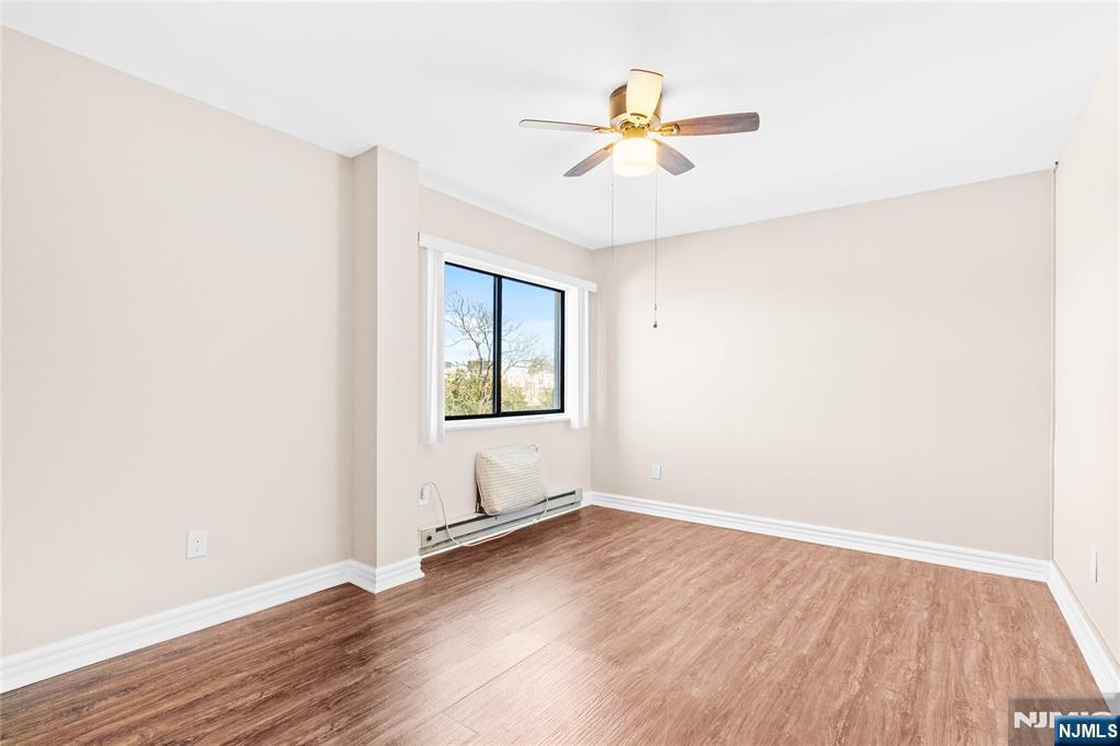 10 Orchard Street, Unit 3E Hackensack, NJ 07601 - Photo 11 of 23 an empty room with wooden floor chandelier fan and windows
