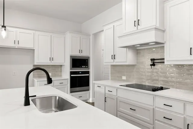 a kitchen with white cabinets a sink and dishwasher