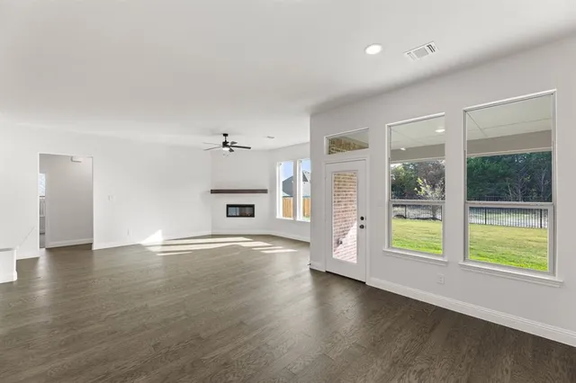 a view of an empty room with a window and wooden floor