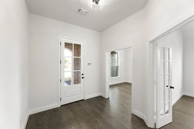 an empty room with wooden floor cabinet and windows