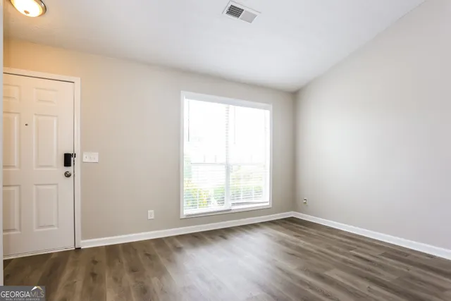 a view of an empty room with wooden floor and a window