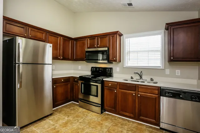a kitchen with stainless steel appliances granite countertop a refrigerator a sink and a stove