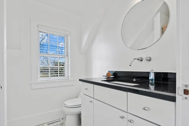 a bathroom with a granite countertop sink a toilet and a mirror