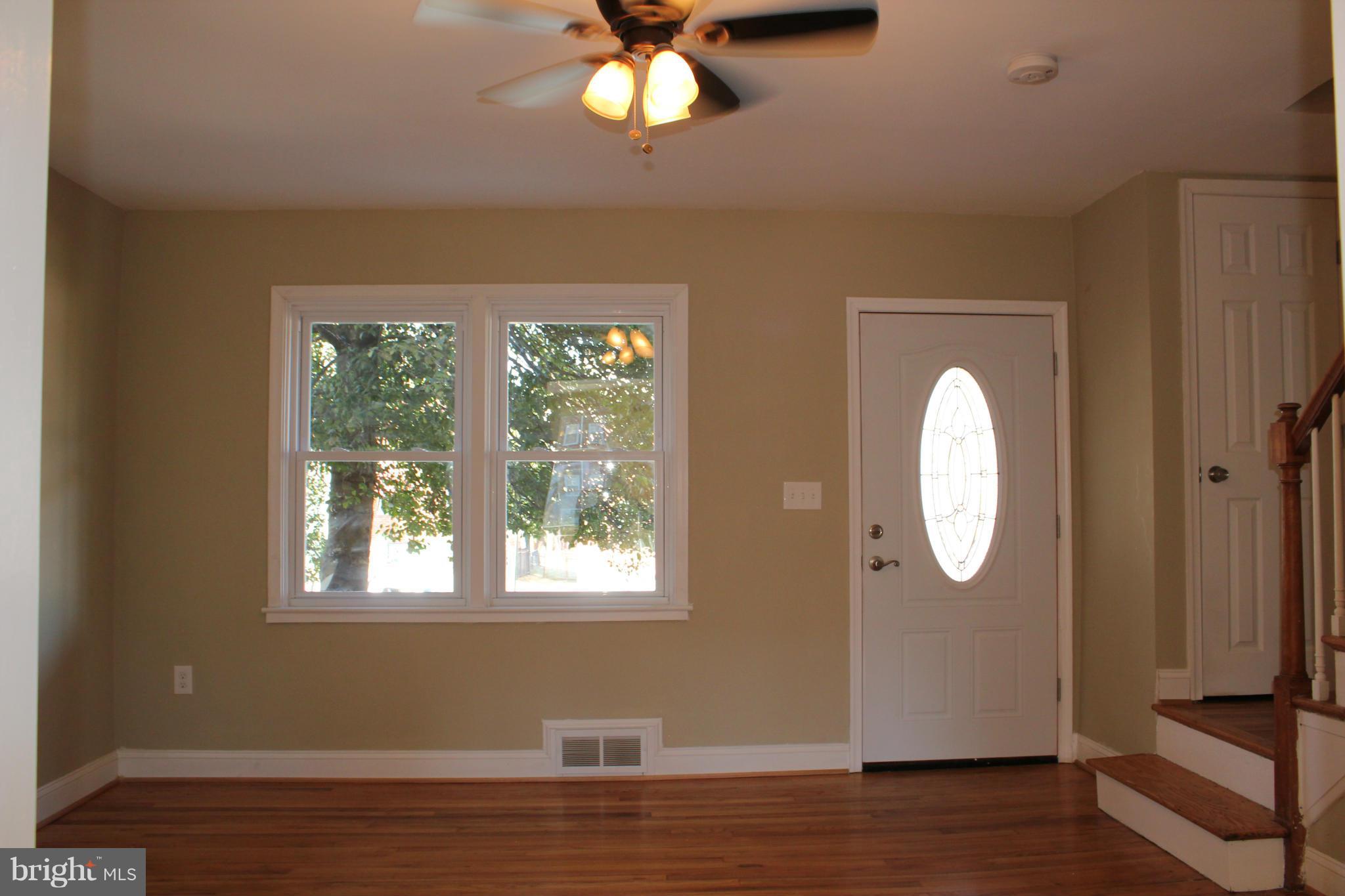 1015 Upnor Road Baltimore, MD 21212 - Photo 3 of 30 an empty room with wooden floor mirror and windows