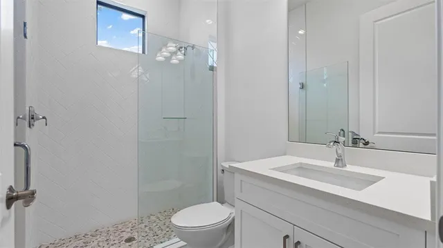 a bathroom with a sink a toilet a mirror and shower
