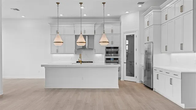 a large kitchen with stainless steel appliances a large counter top a stove a refrigerator and a sink